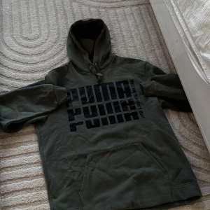 Mörkgrön hoodie från Puma - Säljer en mörkgrön hoodie från Puma med stor svart logga framtill. Tröjan har huva med dragsko och en stor magficka. Perfekt för en avslappnad stil. Endast: 89 kr