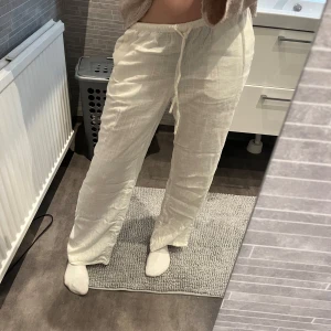 Vita linnebyxor från H&M - Säljer ett par vita linnebyxor. Byxorna har en avslappnad passform och raka ben, perfekta för varmare dagar. Lätta och luftiga i materialet, passar till många olika stilar.