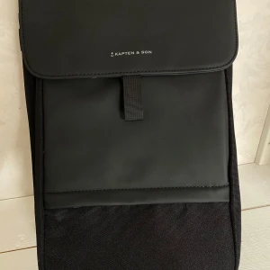 Svart ryggsäck från Kapten & Son - Snygg och stilren svart ryggsäck från Kapten & Son. Oanvänd! Levereras med original dustbag.