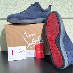 Blå mocka sneakers från Christian Louboutin - Säljer ett par exklusiva blå sneakers från Christian Louboutin i mocka med den ikoniska röda sulan. Skorna har rund tå, snörning och diskret broderad logga på hälen. Fråga gärna vid funderingar. Priset är ej hugget i sten!