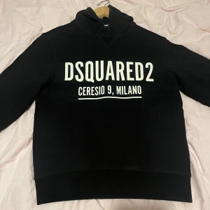 Svart hoodie från Dsquared2 - Säljer en svart hoodie från Dsquared2 med vit text 'DSQUARED2 Ceresio 9, Milano' på bröstet. Klassisk modell med huva och mjukt material, perfekt för en avslappnad stil. Nypris ca3200
