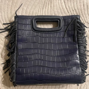 Maje väska - Säljer nu min älskade maje väska då den inte kommer till användning! Den är i övrigt bra skick men de enda defekterna är att tre fransar saknas längst ned  (se bild) samt att handtaget är lite slitet! Men i övrigt ser den bra ut! Nypris ca 3000.