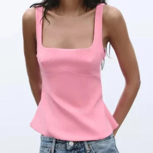 Rosa linnetopp med rosett - Säljer en söt rosa linnetopp med breda axelband och fyrkantig urringning. Toppen har en stor dekorativ rosett i ryggen som ger en extra detalj. Perfekt för att lyfta vilken outfit som helst! Endast använd en gång🩷