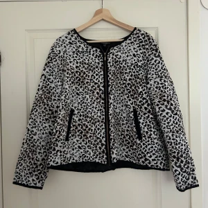 Leopardmönstrad quiltad jacka  - Säljer en snygg leopardmönstrad quiltad tygjacka med svarta kanter och dragkedja framtill. Jackan har lång ärm och två fickor med svarta detaljer. 