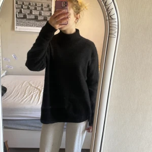 Svart stickad polotröja från First Class Collection - 50kr Mysig svart stickad polotröja från First Class Collection. Tröjan har lång ärm, hög krage och ribbade muddar vid ärmslut och nederkant. Perfekt för kyligare dagar och enkel att matcha med olika outfits.