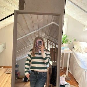 Brandy Melville tröja - Säljer en grön- och vitrandig långärmad pikétröja från Brandy Melville. Tröjan har klassisk krage, knappar framtill och breda ränder. Perfekt för en avslappnad och sportig stil.