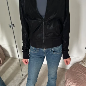 Svart bomberjacka med dragkedja - Säljer en svart karl Lagerfeld bomberjacka med dragkedja framtill. Jackan har lite skimmer 