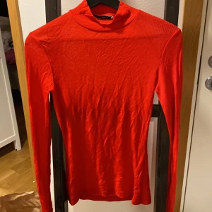 Röd polotröja från Carin Wester - Säljer en röd långärmad polotröja från Carin Wester i storlek XS. Tröjan är figurnära och har en klassisk polokrage. Perfekt att styla med jeans eller kjol för en snygg look.