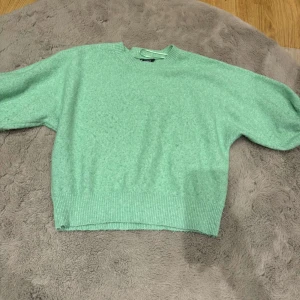 Mintgrön stickad tröja från Lindex - Säljer en mintgrön stickad tröja från Lindex. Tröjan har rund halsringning, långa ärmar och breda ribbade muddar vid ärmslut och nederkant. Perfekt för lager-på-lager och enkel att styla till olika outfits. 