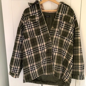Rutig Grön Oversize jacka - Säljer en grön och beige rutig jacka från Boohoo. Jackan har lång ärm, knappar framtill och en beige huva i mjukt material. Perfekt för lager-på-lager och har en avslappnad passform.