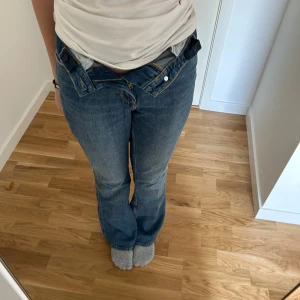 Blå jeans med hjärtformade bakfickor  - Säljer ett par blåa flare jeans från H&M med justerbar midja. Baksidan har två stora hjärtformade fickor som ger en unik look. Jeansen är också större i storleken.