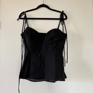 Zara liknande topp - Säljer denna super fina Zara liknande topp, men som tyvärr var för stor för mig. Svart med resår där bak så att den är töjbar, de går även att knyta så man vill vid axlarna vilket också gör de justerbar. Hör av dig vid frågor🥰