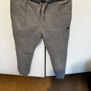 Grå mjukisbyxor från U.S. Polo Assn. - Grå mjukisbyxor från U.S. Polo Assn. med dragsko i midjan och fickor på sidorna. Perfekta för en avslappnad stil och riktigt sköna att ha på sig. Liten logga broderad på ena benet.Barnstorlek