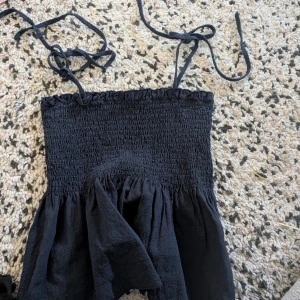 Mörk blå smockad top med tunna axelband stl xs - Säljer en topmed smockad överdel och tunna knytbara axelband.fint skick 