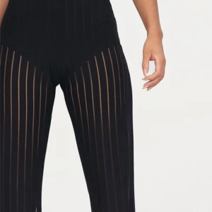 Svarta ribbade byxor från PrettyLittleThing - Säljer ett par svarta ribbade byxor från PrettyLittleThing. Byxorna har hög midja och raka ben med vertikala ribbade ränder som ger en snygg och trendig look. Perfekta att styla med en crop top eller oversized tröja.