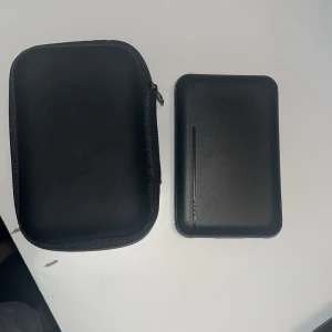 Svart powerbank med fodral - Säljer en svart powerbank tillsammans med ett matchande hårt fodral. Powerbanken  två USB-portar och en micro-USB-port för laddning. Perfekt att ha med sig i väskan när du behöver extra batteri till mobilen.