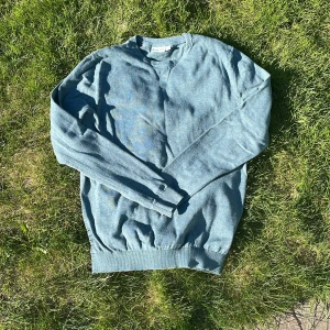 Blå stickad tröja från Kappahl - Mysig blå stickad tröja från Kappahl i storlek S. Tröjan har rund halsringning, långa ärmar och ribbade muddar vid ärmslut och nederkant. Perfekt för kyligare dagar.