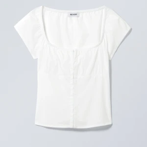 Vit topp med från Weekday - Säljer en vit topp från Weekday med en fyrkantig halsringning och korta ärmar. Toppen har en figurnära passform och är tillverkad i 100% bomullsmaterial. Perfekt till sommaren och enkel att styla till olika outfits. Väldigt populär och slutsåld i alla storlekar. Den är aldrig använd och lappen är kvar!