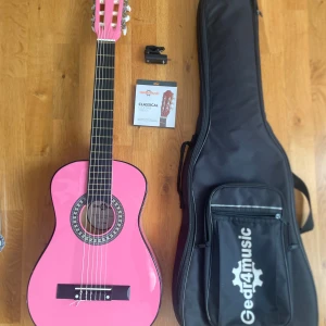 Rosa barngitarr 🩷 - Säljer denna jättefina rosa barn-gitarren (ca 90cm) från Gear4music. Med tillhörande fodral med fack, extra strängar och en fullt fungerande liten maskin som och stämmer gitarren perfekt. Allting är i fint skick 🩷