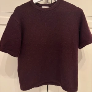 Vinröd stickad kortärmad tröja från Gina Tricot - Mysig vinröd stickad tröja från Gina Tricot med korta ärmar och rund halsringning. Perfekt för lager-på-lager och passar till både jeans och kjol. Enkel och stilren design.