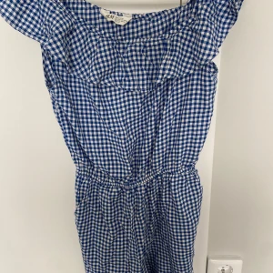 Blåvit rutig klänning med volang från H&M - Supersöt blåvit rutig klänning från H&M med volang upptill och resår i midjan. Perfekt för sommarens alla tillfällen! Klänningen har en luftig passform och är ärmlös för en sval känsla.Har också fickor!Perfekt för 13 åringar