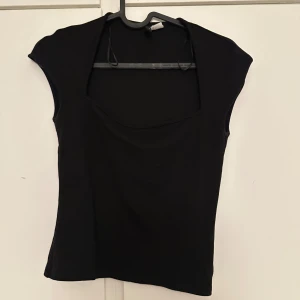 Svart croppad topp - Säljer en svart croppad topp med korta ärmar och rundad halsringning. Enkel och stilren design som passar perfekt till jeans eller kjol. Perfekt basplagg för garderoben!