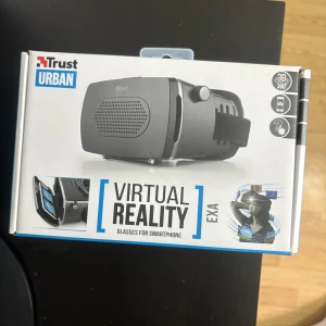 Svarta VR-glasögon Trust Urban EXA - Svarta VR-glasögon från Trust Urban, modell EXA, för smartphone. Justerbart elastiskt band och mjuk vaddering runt ögonen för extra komfort. Linsavståndet kan justeras med ett reglage på sidan. Passar de flesta smartphones.