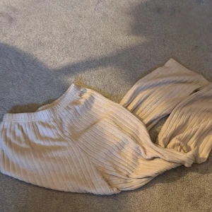 Beige ribbade mjukisbyxor - Superbekväma beige mjukisbyxor med ribbad struktur och resår i midjan. Perfekta för en avslappnad stil och gjorda i ett mjukt, stickat material som känns skönt mot huden.