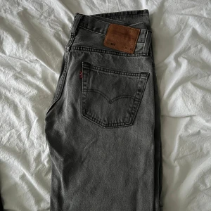 Grå jeans Levis 501 - Säljer ett par klassiska grå Levis 501 jeans med raka ben. Perfekta till vardags för en stilren look.
