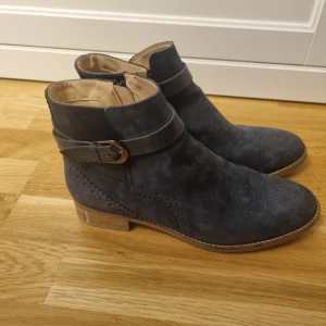 Boots från Clarks  - Mörkblå boots i mocka från Clarks med spänne och dragkedja på sidan