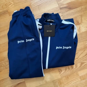 Tracksuit från Palm Angels - Säljer en mörkblå tracksuit från Palm Angels. QR-Kod funkar galant. TOP KVALITET! EXAKT SAMMA PASSANDE MATERIAL‼️PÅSE OCH TAG FINNS KVAR‼️Top skick. Perfekt för att hålla stilen under sommaren. Skick:10/10 