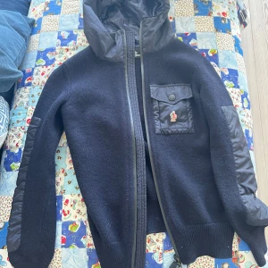  Moncler cardigan - Snygg svart cardigan från Moncler med huva och dragkedja. Jackan har stickade partier, quiltade detaljer på ärmar och bröstficka med knapp och Moncler-logga. Perfekt för kyliga dagar. Passar XS! Kom privat vid minsta funderingar! Självklart äkta😌