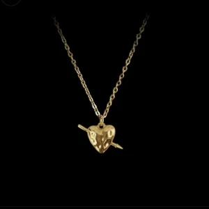 Maria Nilsdotter liknande halsband  - Snyggt halsband i guld med ett hjärthänge som har en pil genom sig. Kedjan är tunn och elegant, perfekt för att ge en cool touch till din outfit. Hjärtat har en unik, lite kantig design.