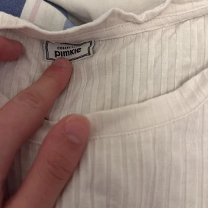 Vit ribbad topp med spets från Pimkie - Säljer en vit ribbad topp från Pimkie med korta ärmar och vacker spetsdetalj längst ner. Toppen har en mjuk och bekväm känsla, perfekt för att lyfta din outfit med en feminin touch.