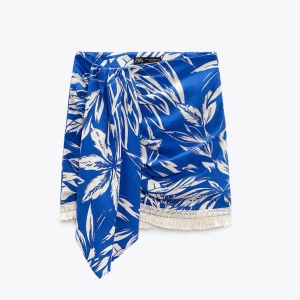 Blåvit omlottkjol med fransar från Zara - Säljer en blåvit omlottkjol från Zara med somriga blad mönster. Kjolen som är köpt för ett tag sedan är använd 1 gång och är i toppen skick. Stolek S men är mer en XS. Super fin och super sommrig🩵