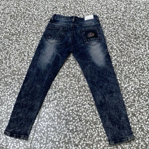 Mörkblå tvättade jeans med broderad detalj - Snygga mörkblå jeans med tvättad effekt och broderad detalj på bakfickan. Klassisk femficksmodell med smal passform och normal midja. Perfekta för en trendig vardagslook.