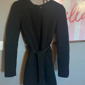 Svart kappa  med bälte - Säljer en svart kappa med lång ärm och knytbälte i midjan. Kappan har en enkel och stilren design. Använd men inga defekter. Kommer från vero moda.