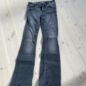 Grå bootcut jeans - Säljer ett par grå bootcut jeans med klassisk femficksdesign och normal passform. Jeansen har låg midja och är tillverkade i ett mjukt denimtyg. Perfekta för dig som gillar en avslappnad men ändå stilren look.