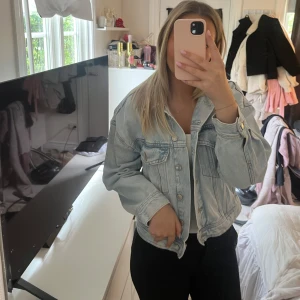 Ljusblå jeansjacka från Pull&Bear - Säljer en ljusblå jeansjacka från Pull&Bear i klassisk modell. Jackan har knappar framtill, två bröstfickor. Perfekt att slänga över en t-shirt eller hoodie för en avslappnad look. Jättefint skick!!🩷