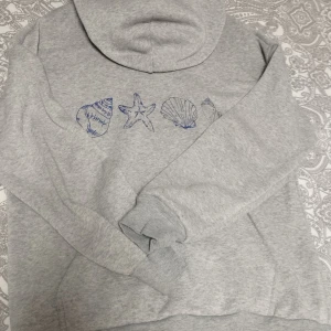 Grå hoodie med tryck - Fin hoodie med snäckskalstryck på framsidan. Använd ett fåtal gånger.