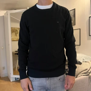 Svart tröja från Calvin Klein - Säljer en stilren svart tröja från Calvin Klein i en mjuk bomulls- och silkesblandning. Tröjan har rund halsringning och långa ärmar, perfekt för en clean och klassisk look.