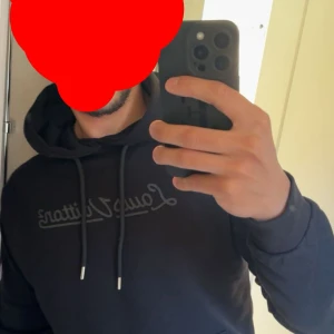 Svart hoodie från Louis Vuitton - Säljer en svart hoodie från Louis Vuitton med diskret logga framtill och stor logotyp på ryggen. Tröjan har huva med dragsko och långa ärmar. Perfekt för dig som gillar stilrena märkesplagg. Använd 1 gång bara. Passar mer S