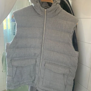 Grå dunväst från Stenströms - Säljer en grå dunväst från Stenströms med huva och dragkedja framtill. Storlek XL. Väldigt fint skick. Tar bud!