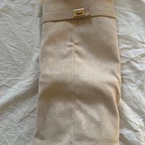 Beigea boots med bälte - Snygga beiga boots med bälte runt från Lululia. Säljer för att jag inte fick en användning för de och blev lite för lång för min smak. De är använda en gång hemma när de skulle testas.💞 Nypris är 600.