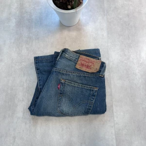 Blåa Levi jeans - 👖 Levi’s 501 – Klassiska Blå Jeans i Tidlös Stil Säljer ett par Levi’s 501 i blå denim med raka ben och knappgylf. Femficksdesign, tydliga sömmar och den ikoniska läderpatchen bak i midjan – en riktig klassiker som aldrig går ur tiden.  📏 Storlek: W28 L32 🧵 Skick: Mycket bra stick 💸 Pris: Endast 149 kr! 🛍️ Originalpris: 800–1000 kr  Perfekta för dig som gillar slitstarka jeans och tidlös stil. 📩 Skicka DM om du vill köpa!