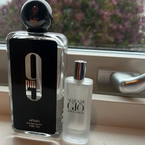 BYTE!!! - Två parfymflaskor: Afnan 9pm i en stor, rektangulär glasflaska med svart etikett och rund svart kork samt Acqua di Giò från Giorgio Armani i en mindre, frostad glasflaska med silverfärgad kork. Båda flaskorna har stilren design.9 pm har 35ml och acqua di gio giorgio armani har 2ml kvar