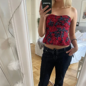 Röd blommig tubtopp -  röd tubtopp med blommigt mönster och lätt volang nertill💕