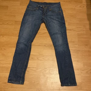 Levi's blå jeans straight fit - Klassiska blå jeans från Levi's med raka ben och fem fickor. Jeansen har normal passform och är tillverkade i slitstarkt denimtyg. Perfekta för en avslappnad stil och passar till det mesta.