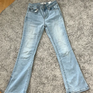 Ljusblå bootcut jeans - Säljer ett par  ljusblå jeans med låg midja och bootcut passform och klassisk femficksdesign. Jeansen har normalhög midja och dragkedja med knapp framtill. Perfekta för en avslappnad och trendig look.