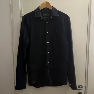 Mörkblå Morris skjorta - Säljer en stilren mörkblå skjorta från Morris i storlek S. Skjortan har använts ett fåtal gånger så den är i väldigt bra skick. Perfekt för dig som gillar en snygg och stilren look till fest eller bara i vardagen.